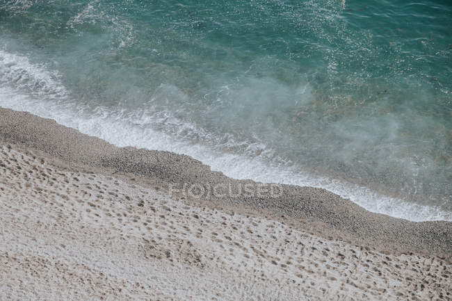 Olas de marea llegando a la playa de arena - foto de stock