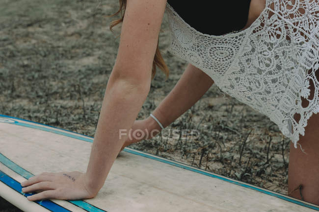 Surfer girl wipes her surfboard — Stock Photo