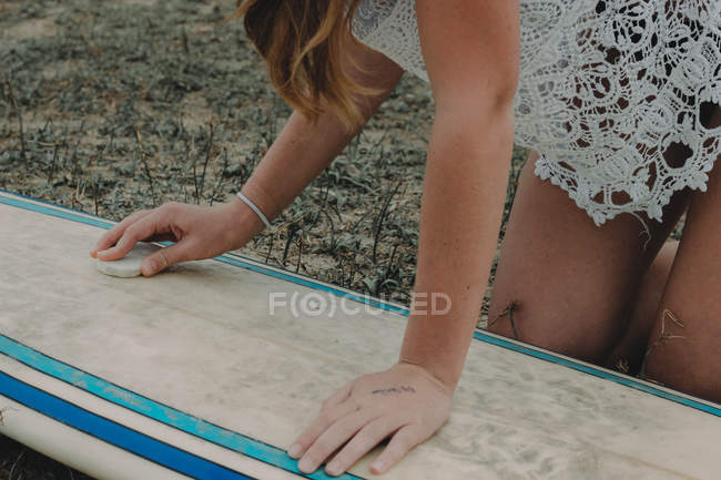 Surfer girl wipes surfboard — Stock Photo