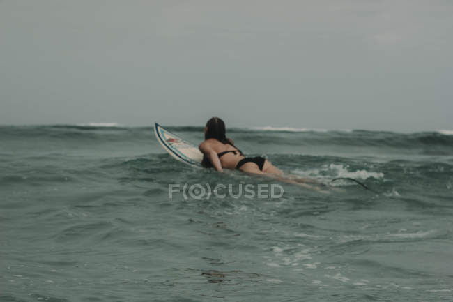 Girl with surfboard in the ocean — Stock Photo