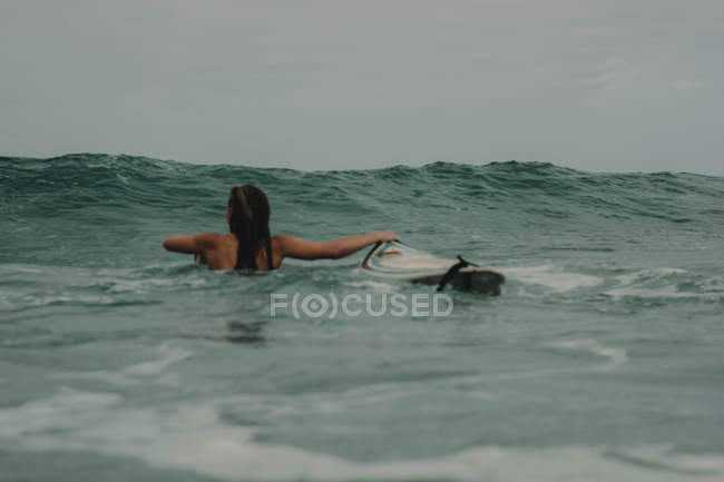 Surfer girl with surfboard in the ocean — Stock Photo