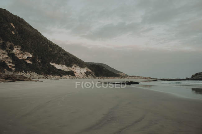 Costa rochosa com praia arenosa — Fotografia de Stock