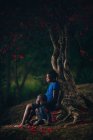 Menina e menino sentado debaixo da árvore — Fotografia de Stock