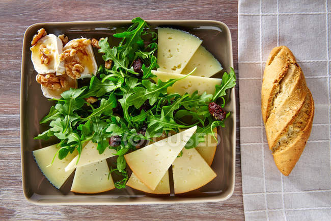 Ensalada de rúcula con miel de queso de cabra y frutos secos - foto de stock