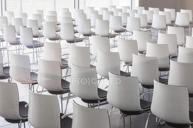 Cadeiras brancas vazias na sala de conferências contemporânea com — Fotografia de Stock