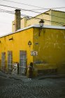 Woman leaning on wall of yellow building — Stock Photo