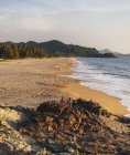 Spiaggia di sabbia con acqua ondulata sopra cieli limpidi durante il giorno — Foto stock