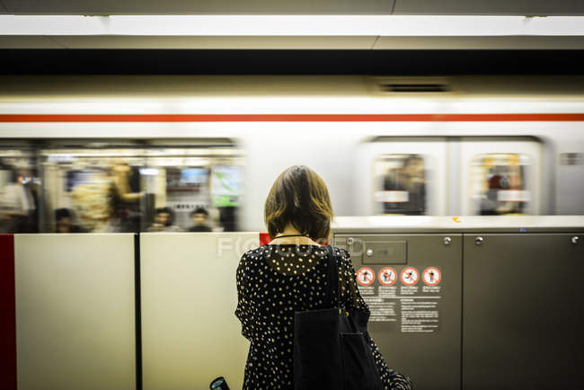 Девушка стоит перед движущимся поездом — стоковое фото