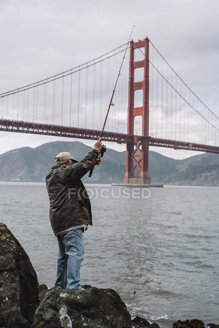 Uomo pesca vicino Golden Gate Bridge — Foto stock