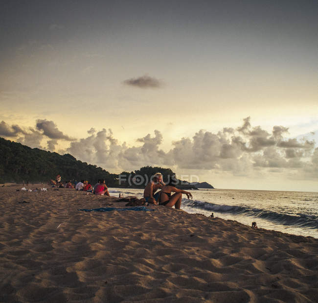 Люди сидят на песчаном пляже — стоковое фото