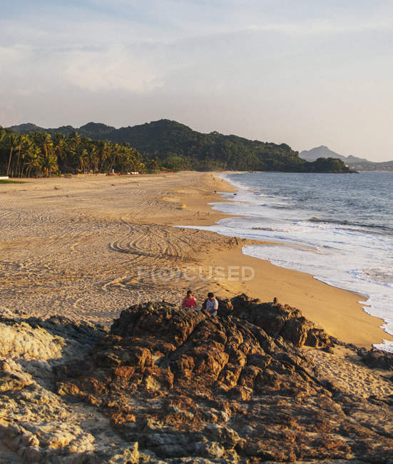 Praia de areia com água ondulada sobre céus claros durante o dia — Fotografia de Stock