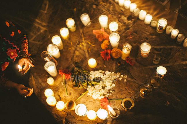 Woman with laming candle in hand and flowers on ground surrounded by ritual candles, Mexico, Rancho Trinidad — Stock Photo