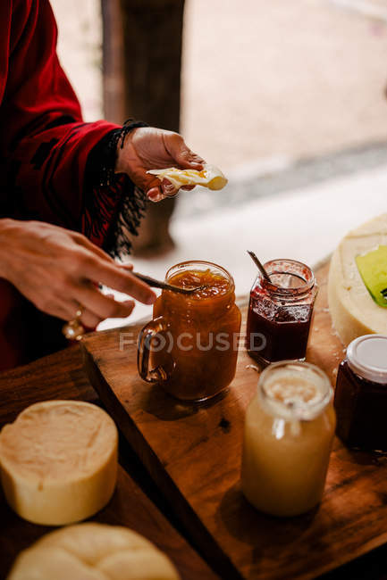 Mujer manos con cuchara tomando mermelada - foto de stock