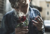 Mann raucht und hält Rose — Stockfoto
