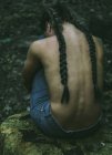 Femme assise dans la forêt avec les mains autour des jambes — Photo de stock