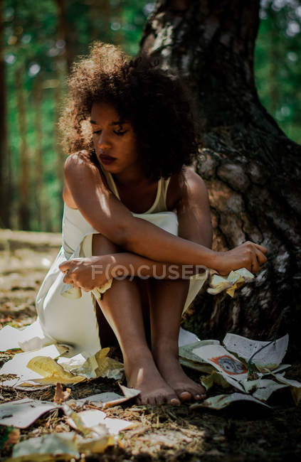 Donna triste con le pagine strappate nella foresta — Foto stock