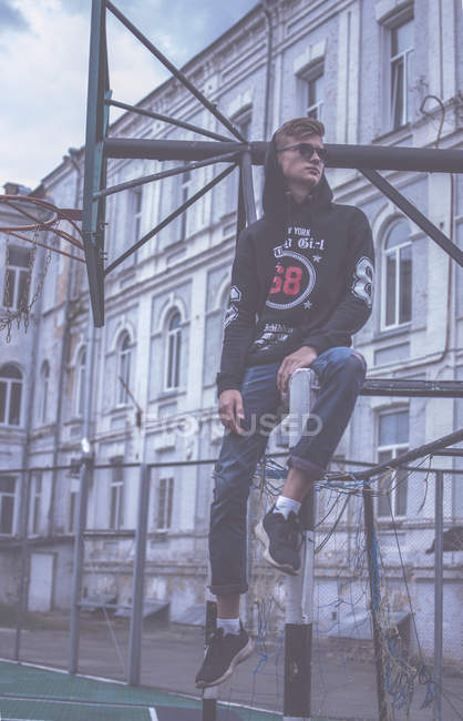 Hipster man sitting on basketball court outdoor — Stock Photo