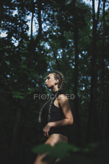 Femme debout dans la forêt et regardant loin — Photo de stock
