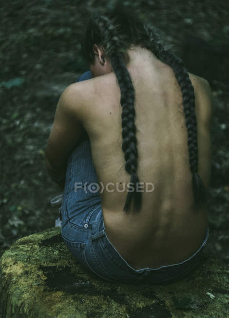 Donna seduta nella foresta con le mani intorno alle gambe — Foto stock