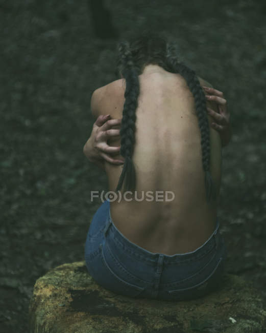 Напіводягнена жінка сидить у лісі — стокове фото