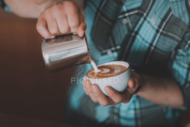 Barista pouring milk into coffee — Stock Photo