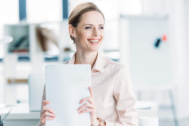 Smiling businesswoman holding documents at office — Stock Photo