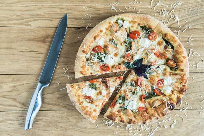 Italian pizza with knife on wooden tabletop — Stock Photo