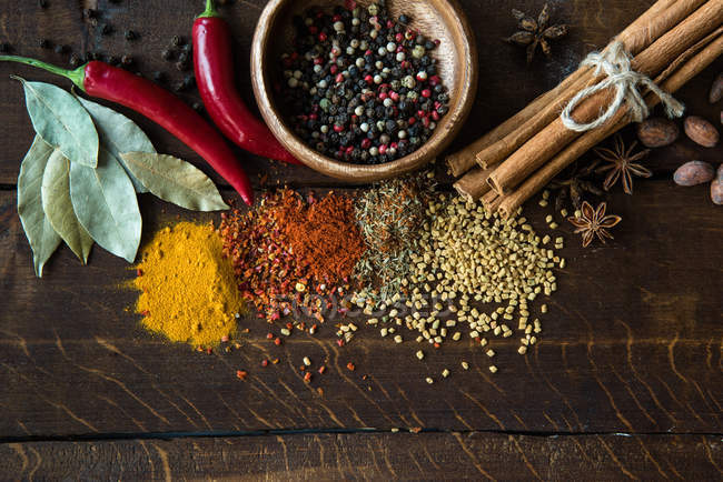 Pepper in bowl with scattered herbs and spices — Stock Photo