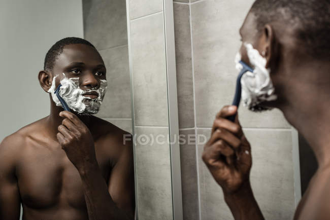 Thoughtful african-american man shaving — Stock Photo