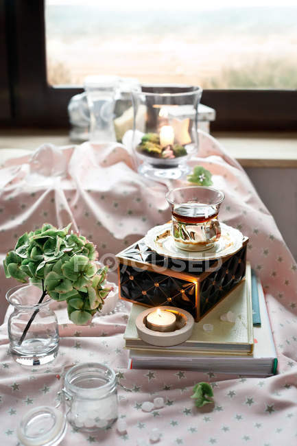 Tasse de thé dans un cadre romantique avec bougies et fleurs — Photo de stock