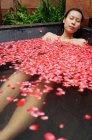 Frau in Wanne mit Rosenblättern — Stockfoto