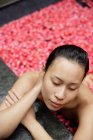 Mujer en bañera con pétalos de rosa - foto de stock