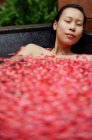 Femme dans la baignoire avec des pétales de rose — Photo de stock