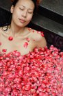 Женщина в ванне с лепестками роз — стоковое фото