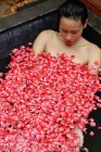 Mujer en bañera con pétalos de rosa - foto de stock