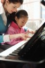 Girl learning to play piano with tutor — Stock Photo