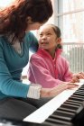 Дівчина вчиться грати на піаніно з репетитором — стокове фото