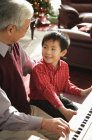 Дедушка и внук играют на пианино — стоковое фото