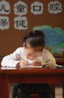 Schoolgirl writing in workbook at class — Stock Photo