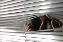 Man looking through silver blinds. — Stock Photo
