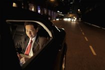Businessman sitting in back seat of car — Stock Photo