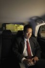 Uomo d'affari seduto in auto e al lavoro sul computer portatile — Foto stock