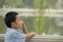 Giovane ragazzo guardando il lago . — Foto stock