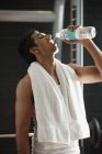 Mann trinkt Wasser in Turnhalle — Stockfoto