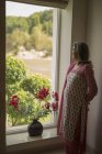 Donna matura che guarda fuori dalla finestra — Foto stock