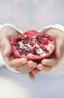 Hands holding pomegranate — Stock Photo