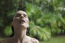 Mulher de pé no chuveiro de chuva tropical — Fotografia de Stock