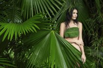 Mulher atrás de grandes folhas tropicais — Fotografia de Stock
