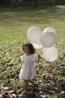 Chica en el parque, con globos - foto de stock