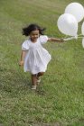 Criança correndo com balões brancos — Fotografia de Stock